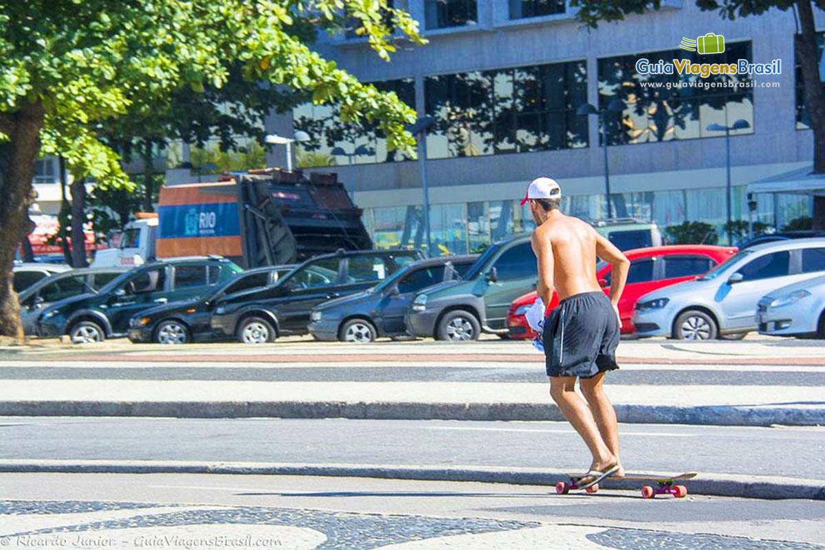 Imagem de uma pessoa andando de skate no calçadão da praia.