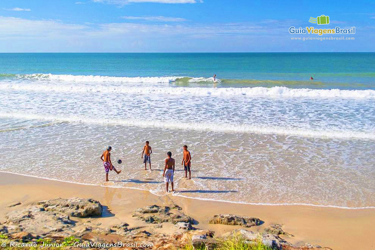 Imagem de pessoas jogando bola na areia da Praia Cotovelo. 