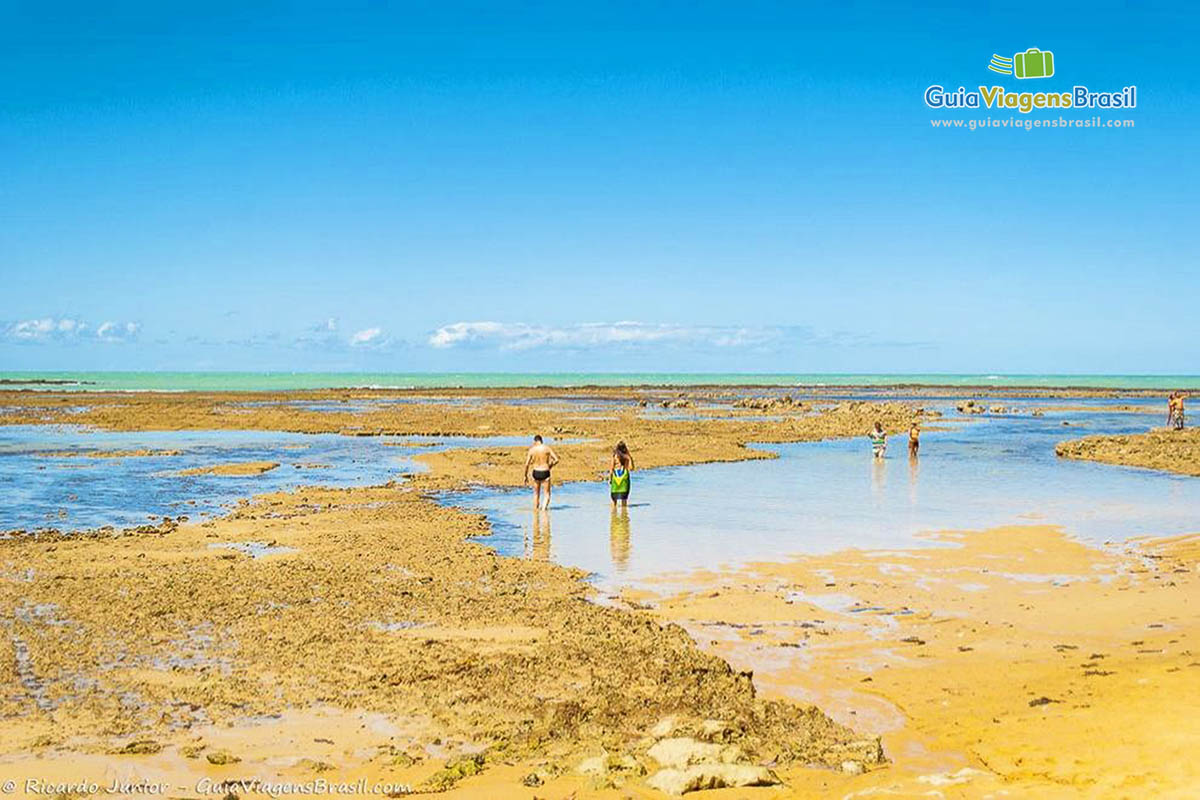 Imagem de turistas aproveitando a maré baixa e curtindo as piscinas naturais.