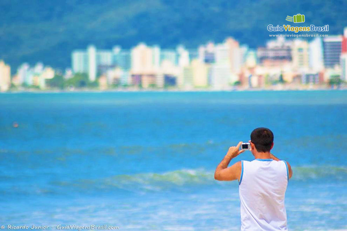 Imagem de um rapaz tirando foto da Praia Itapema.