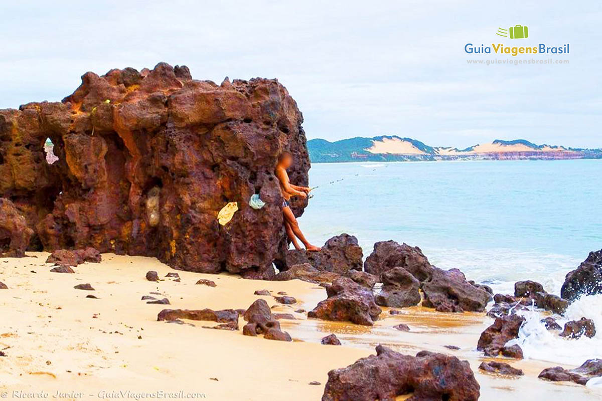 Imagem de turistas encostado nas pedras da Praia Pipa.