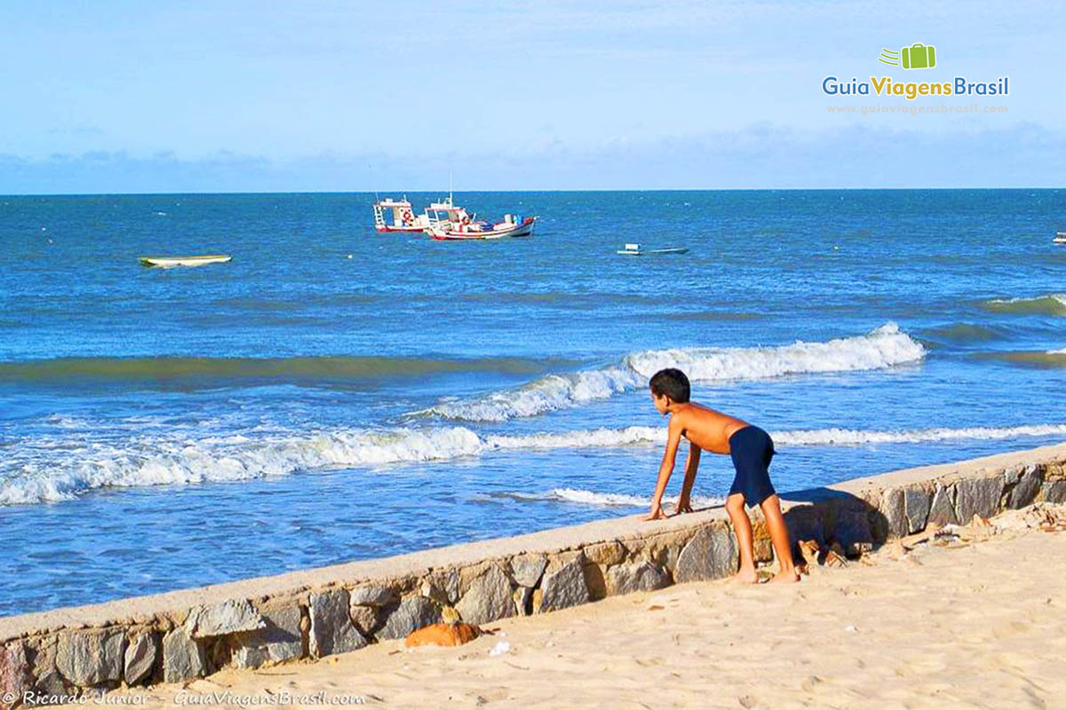 Imagem de um menino olhando para mar da Praia do Pitangui.
