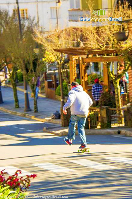 Imagem de um rapaz andando  de skate no centro.