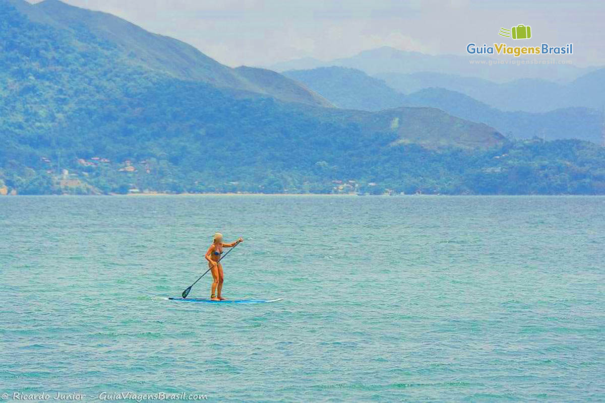 Imagem de uma pessoa praticando stand up paddle em em Ilhabela.