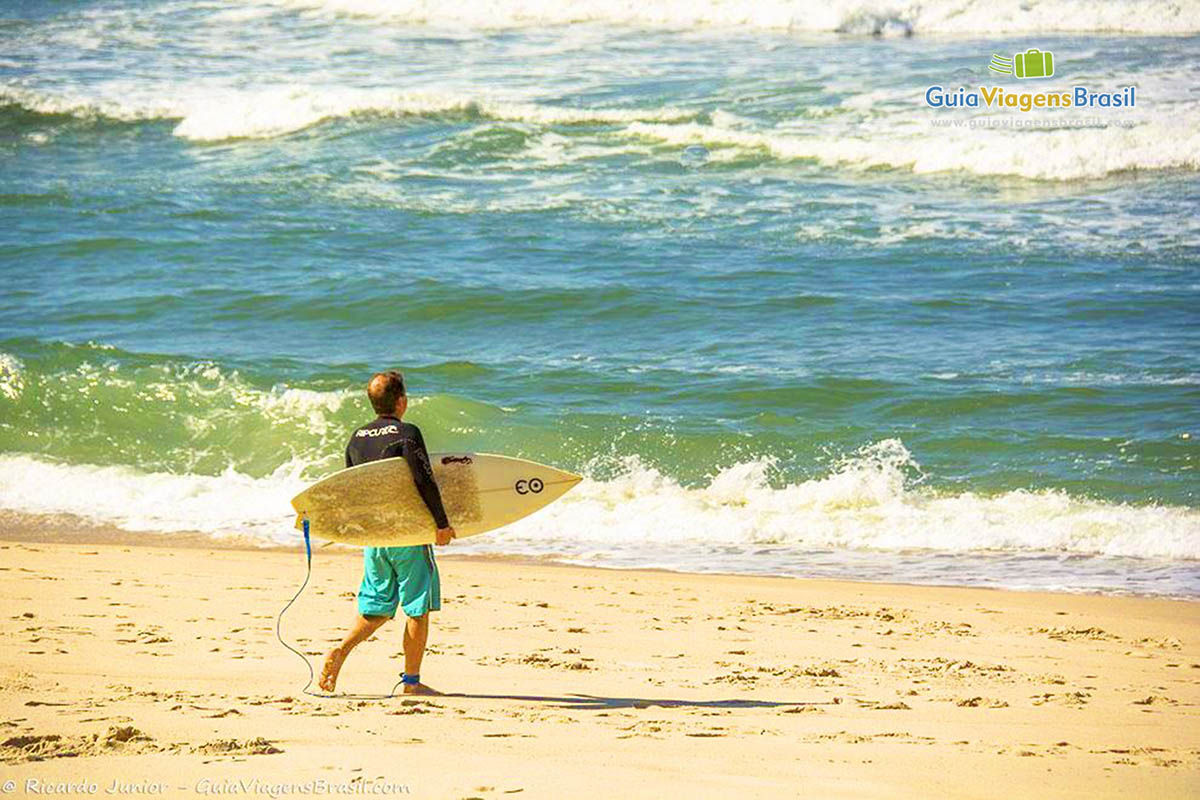Imagem surfista entrando no mar  com sua prancha.