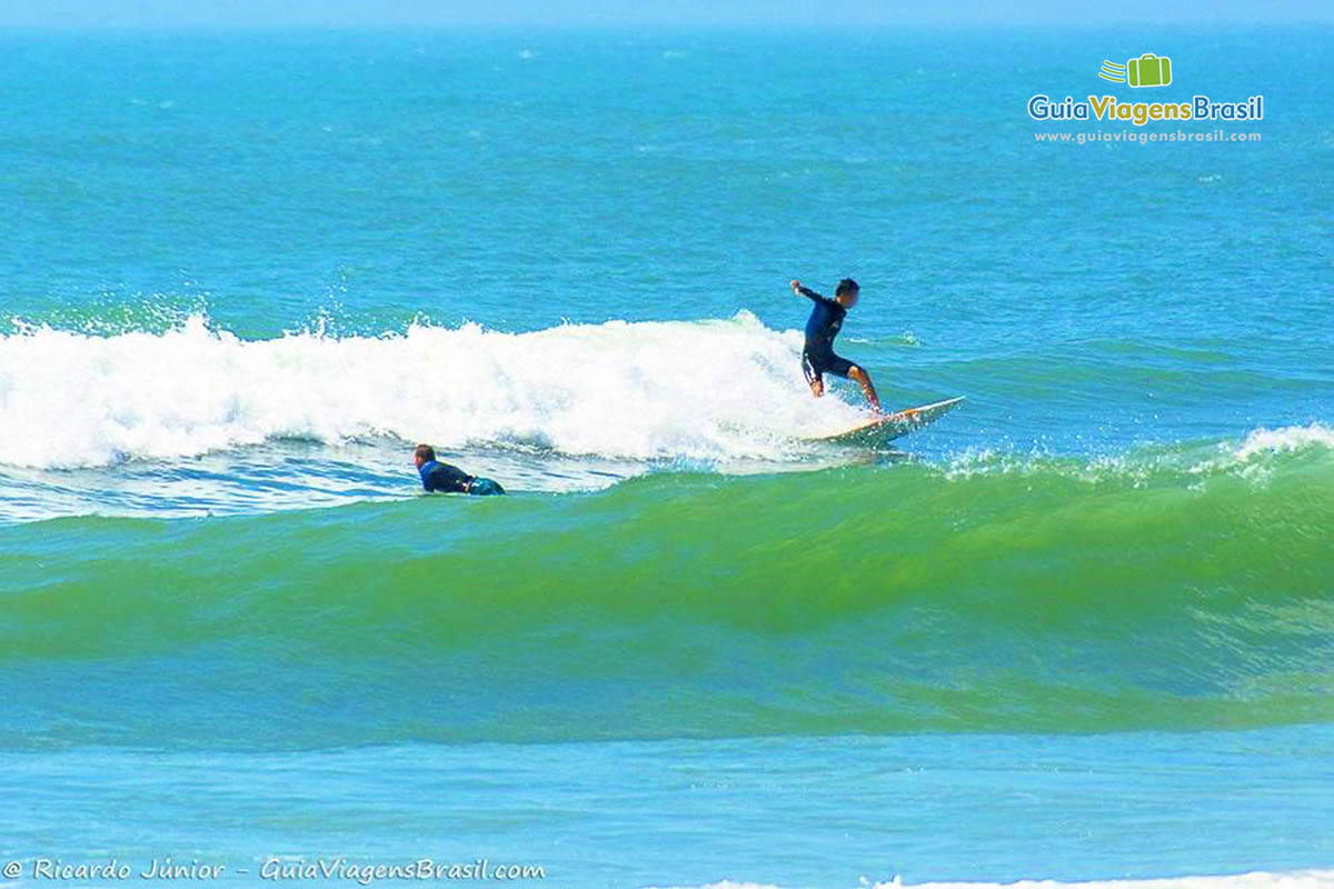 Imagem de surfistas aproveitando belo dia de ondas na Praia Ferrugem.
