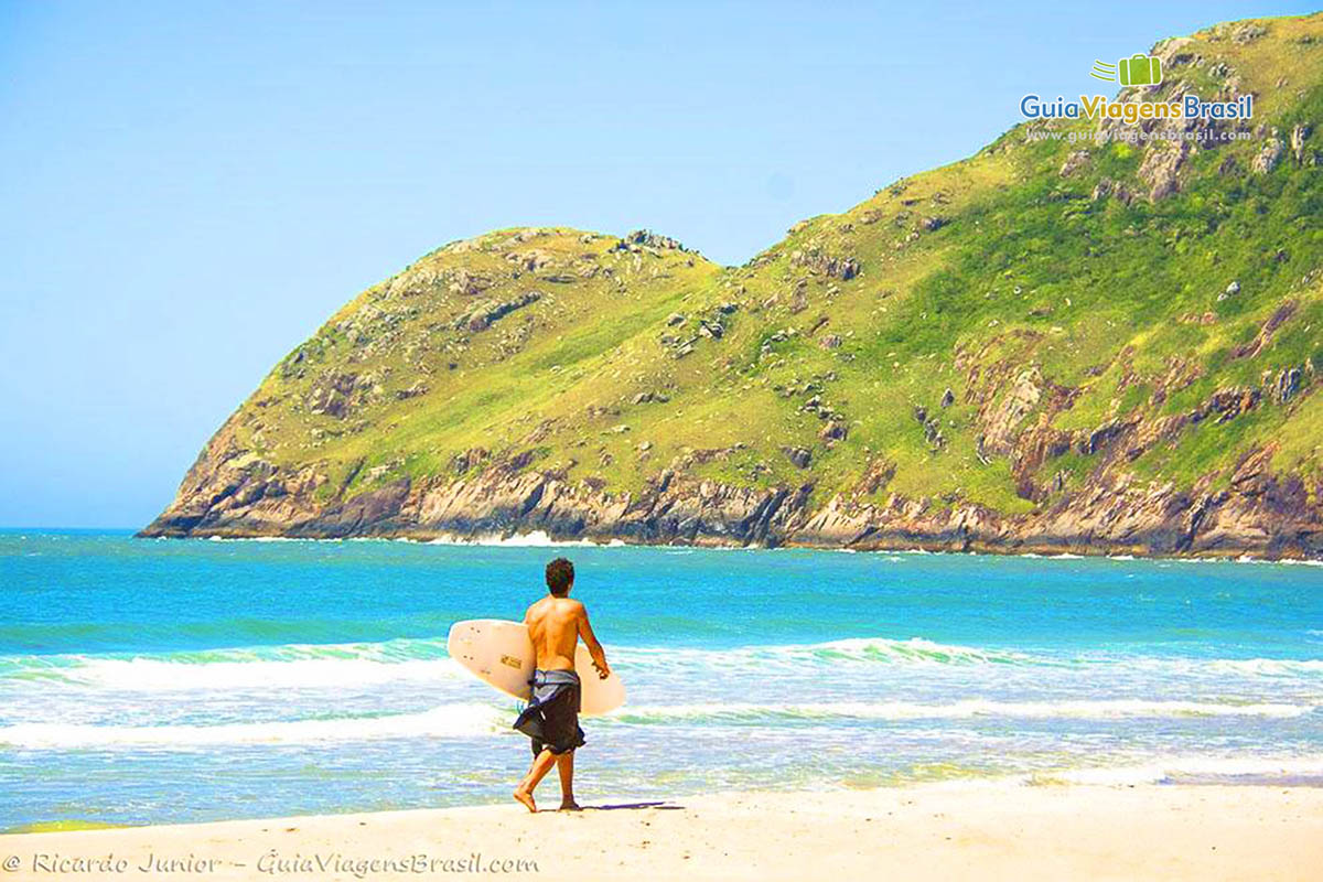 Imagem de surfista andando com sua prancha na areia da praia
