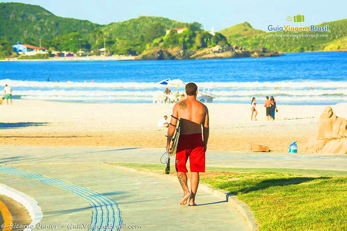 Imagem de um surfista andando na Praia do Forte.