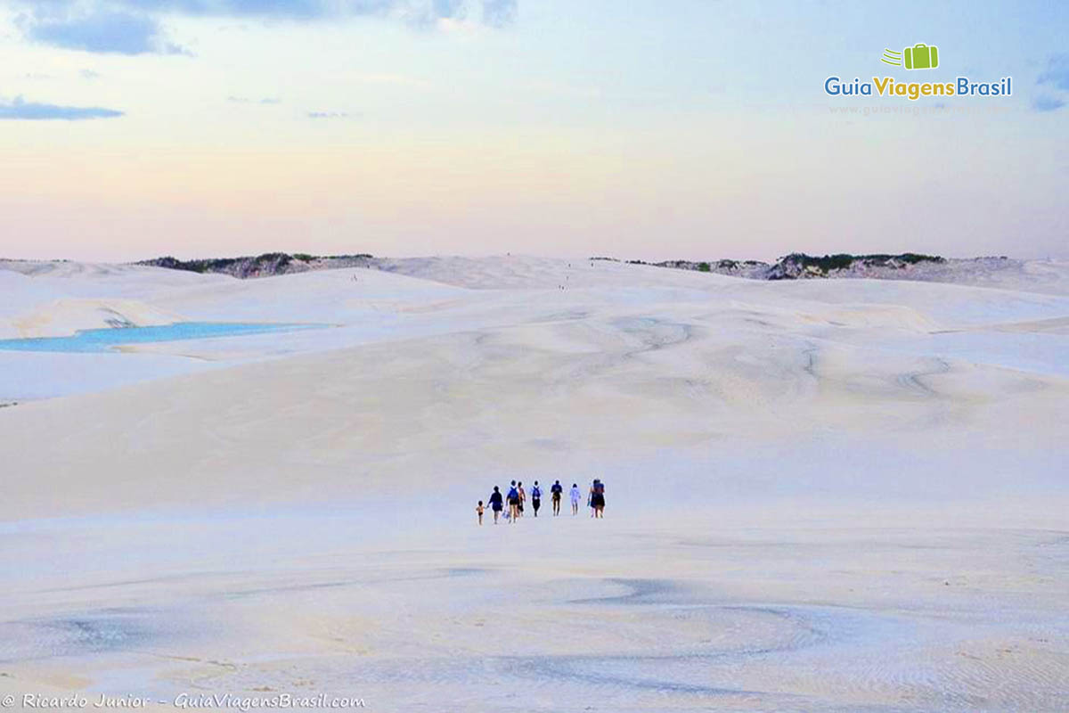 Imagem de turistas andando nas areias brancas como algodão.
