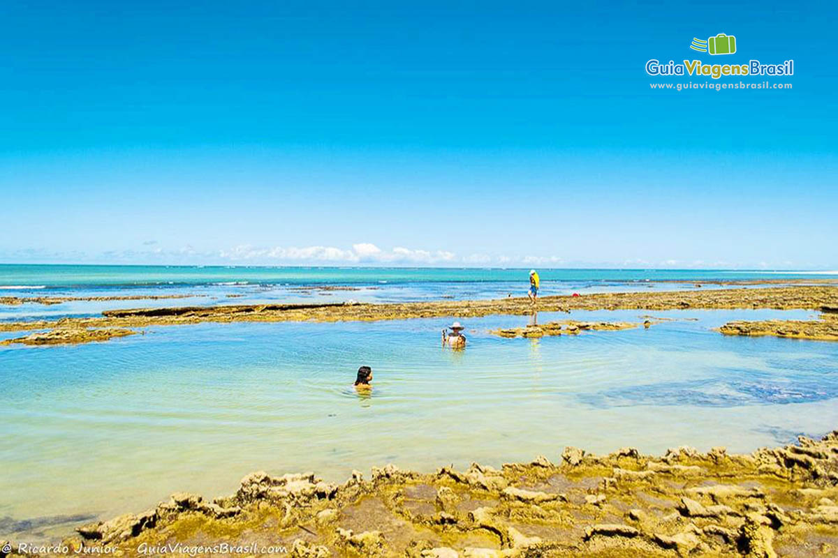 Imagem de turistas nas águas transparentes na Praia Carneiro.