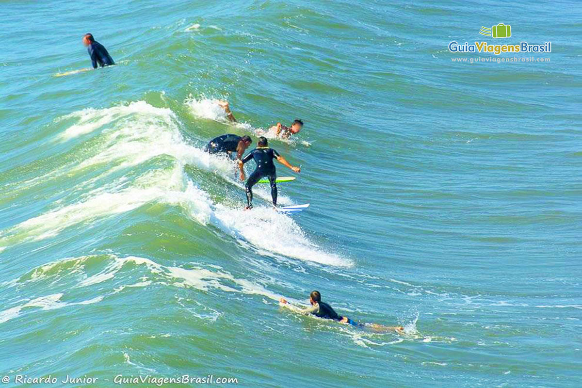 Imagem de vários surfistas no mar da Praia da Barra.