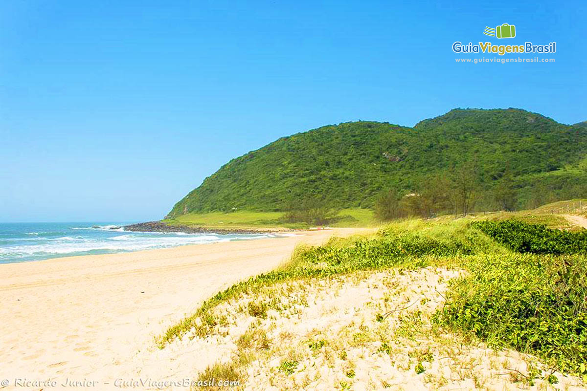 Imagem de uma larga faixa de areia da Praia Silveira.