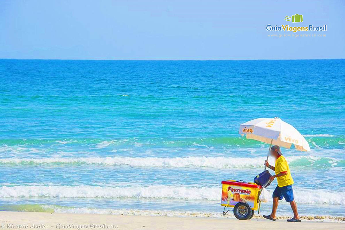 Imagem de um vendedor de sorvete com seu carrinho nas areias da Praia Juquehy.