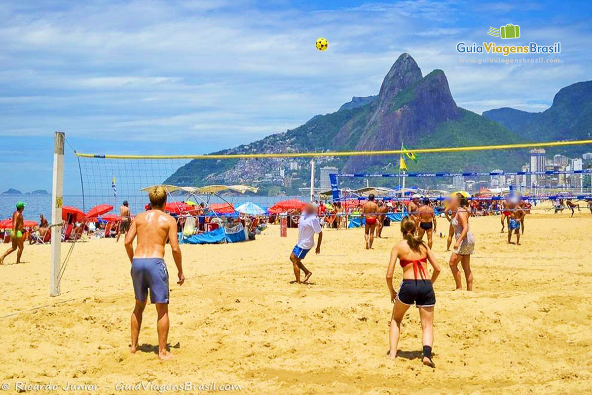 Imagem de amigos jogando vôlei nas areias da praia.